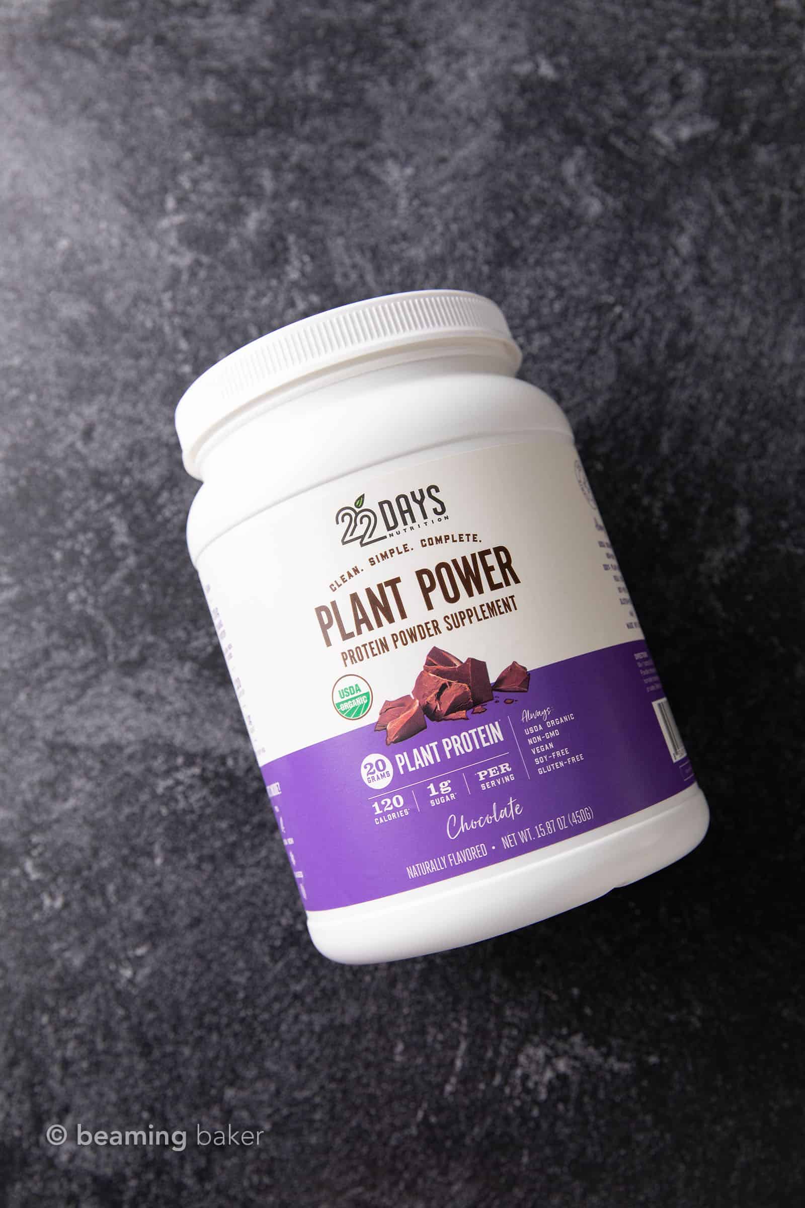 Container of 22 Days Nutrition vegan chocolate protein powder on grey background
