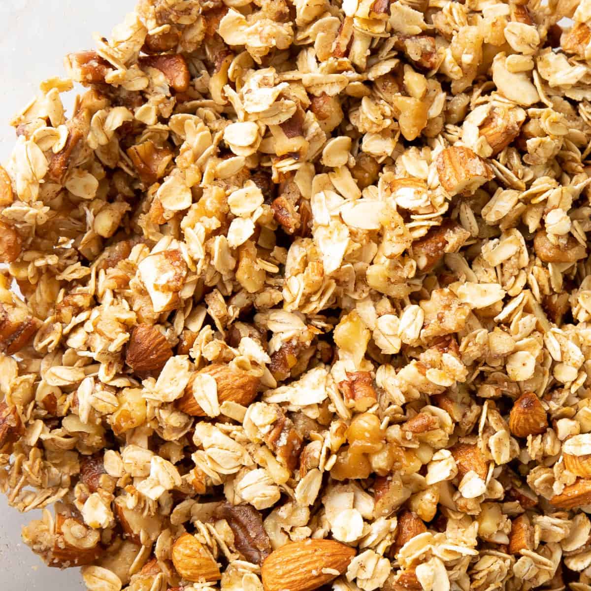 super close up of oats, nuts, and maple syrup in a mixing bowl