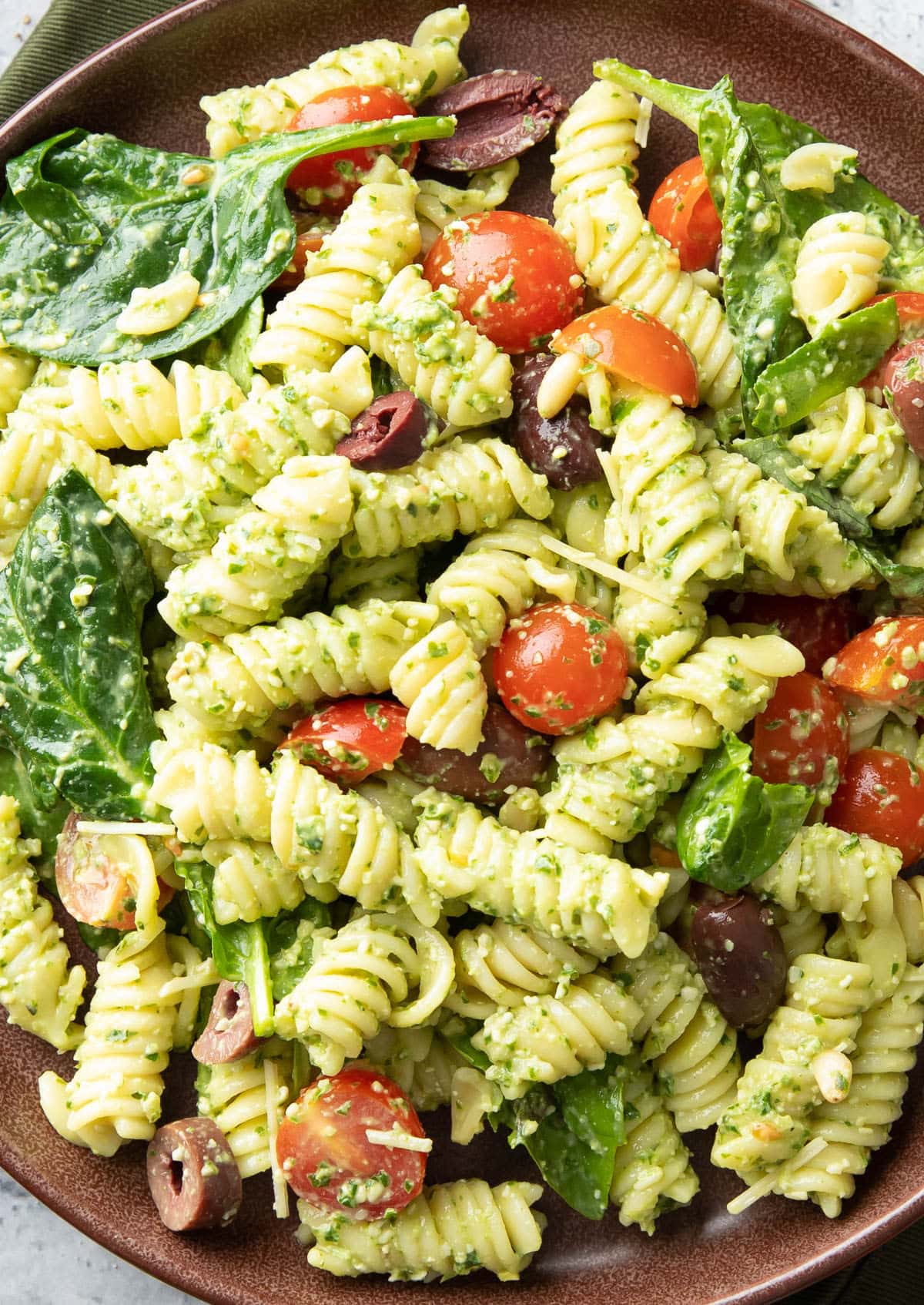 super close up of this Italian side dish with cherry tomatoes, fresh spinach on rotini pasta