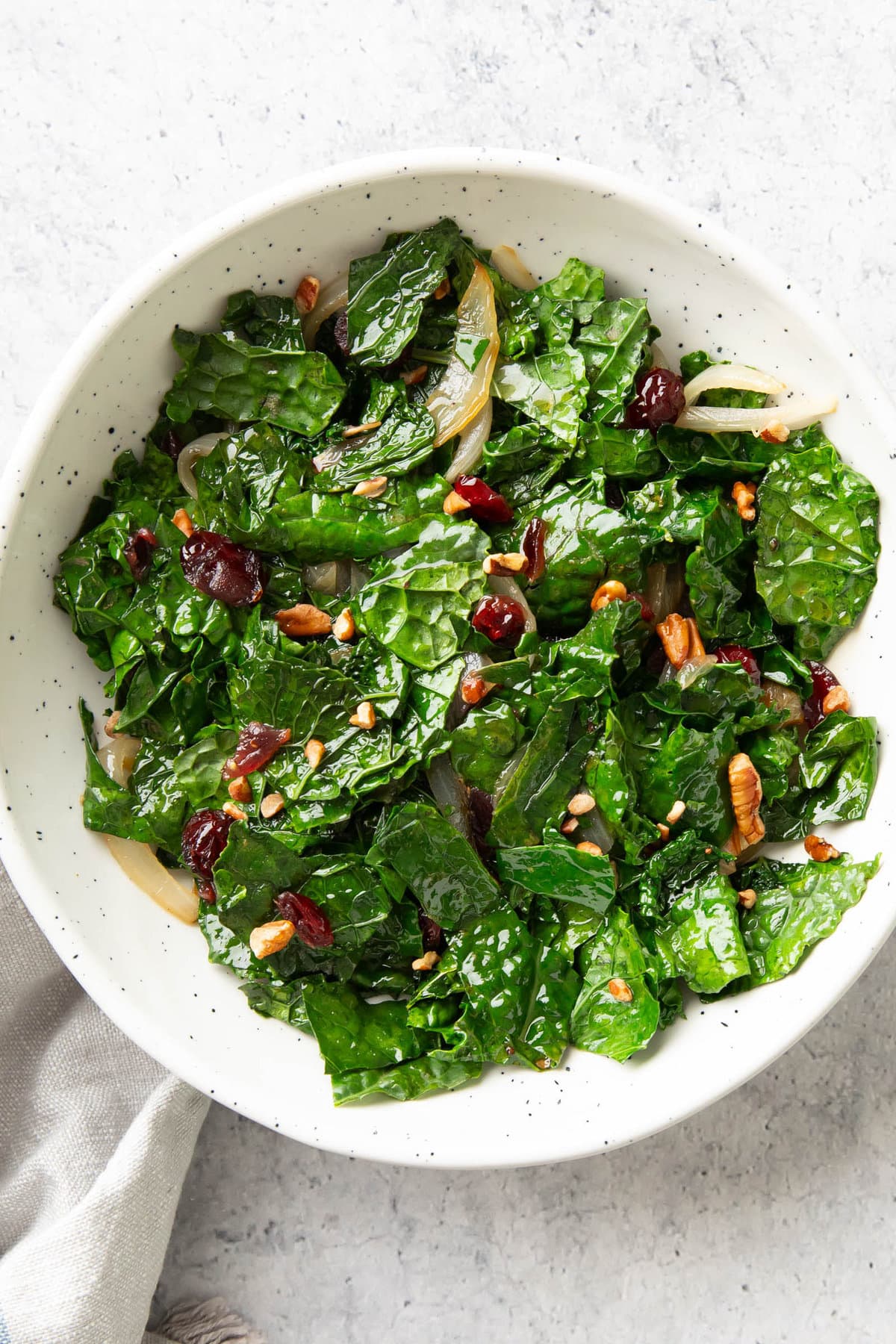 sautéed kale with cranberries and pecans served in a white bowl