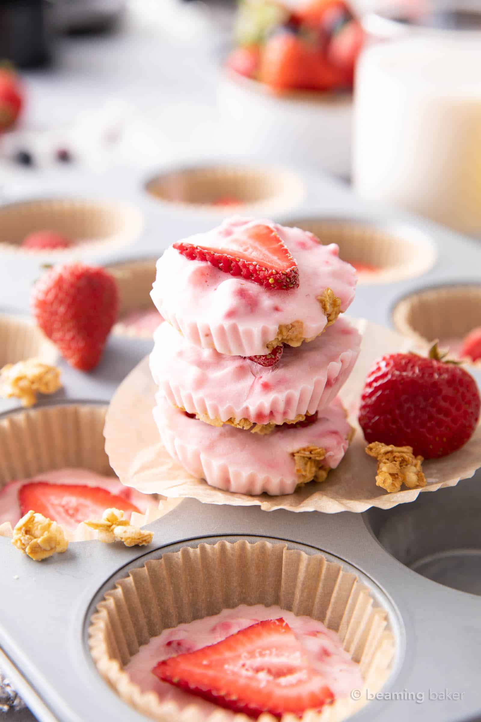Stack of three strawberry bites on parchment with granola clusters